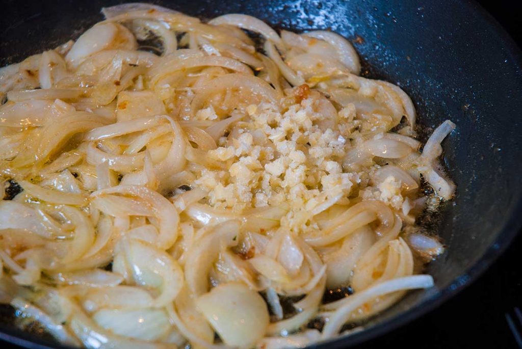 Adding chopped garlic to caramelised onions.