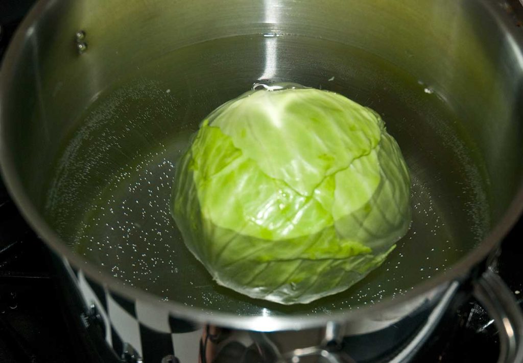 Cabbage being boiled in a pot, softening the leaves for stuffing.