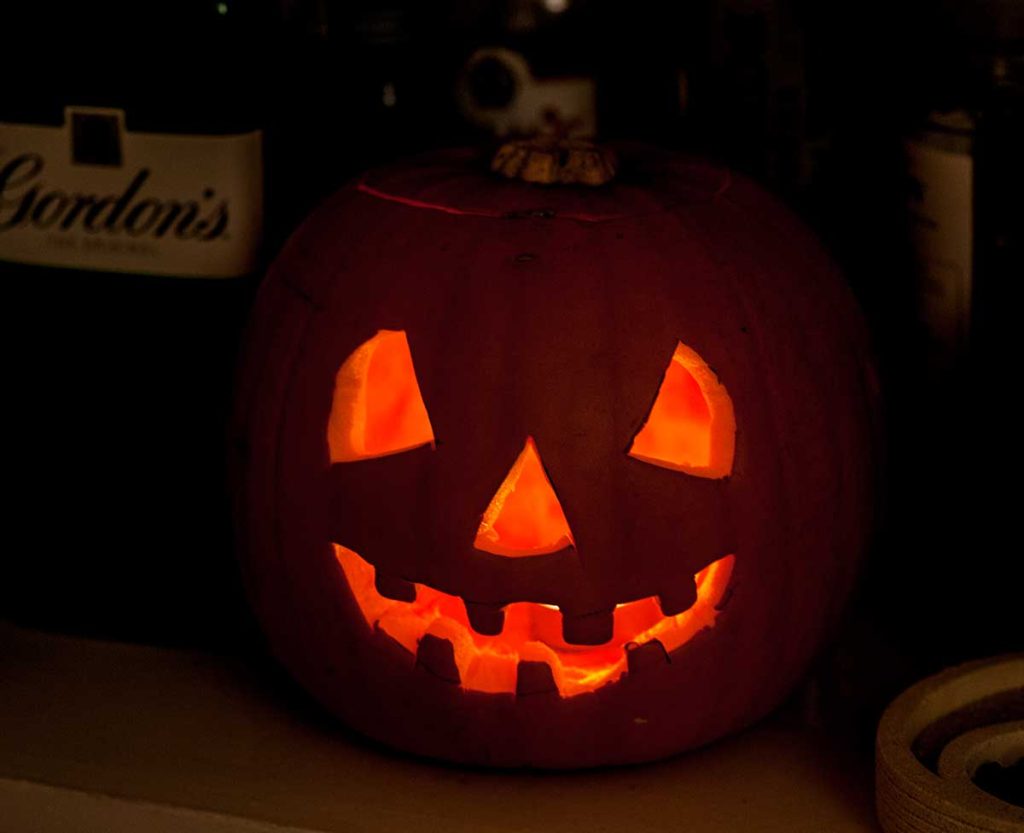 Glowng carved pumpkin, spooky face , with a lit candle inside. 