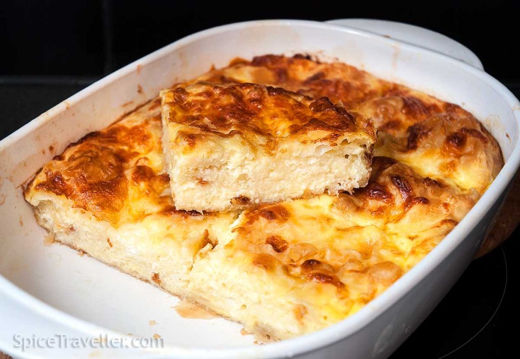 Perfectly baked Banitsa with a golden, crisp top, one slice cut out and placed on top of the rest of the banitsa.