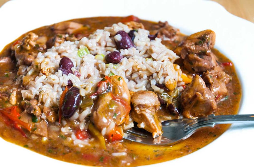 Close up of Simple Caribbean style spicy brown chicken stew served with coconut rice and beans.