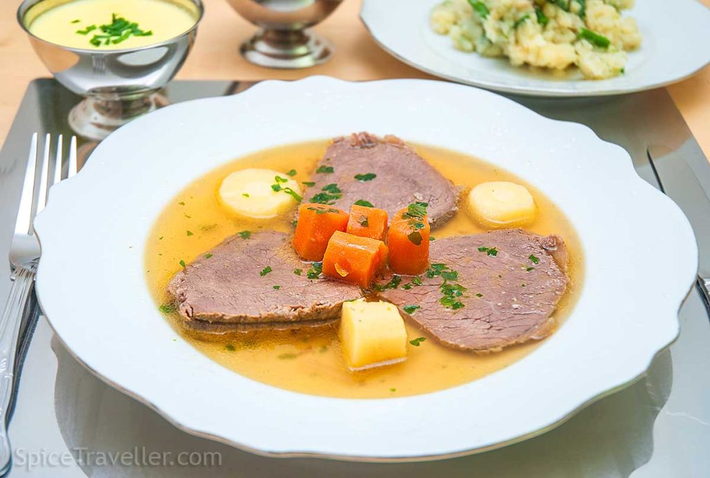 Viennese elegant presentation of 3 slices of boiled beef served with pieces of carrot and parsnip with dlicious golden broth.