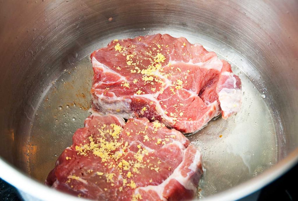 Frying pork steaks for Bavarian style sauerkraut dish.