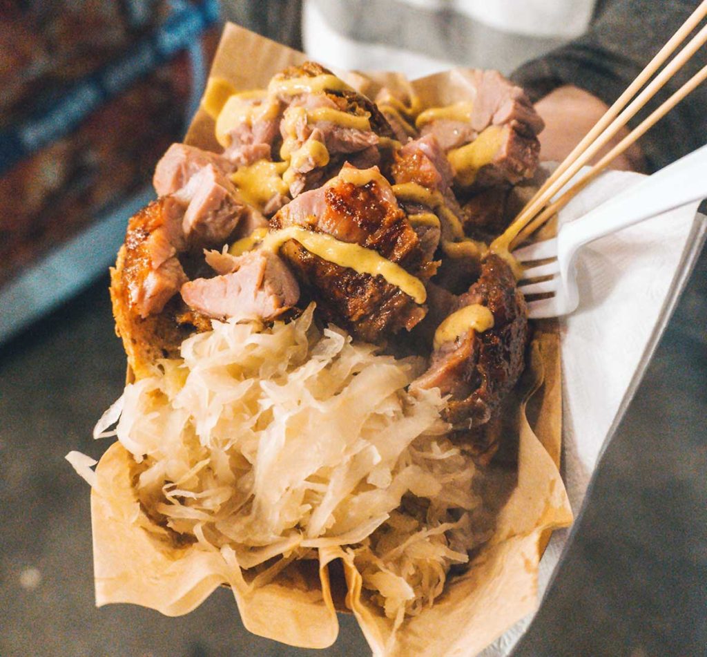 German street food - sauerkraut with roasted pork chunks, drizzled with curry sauce.