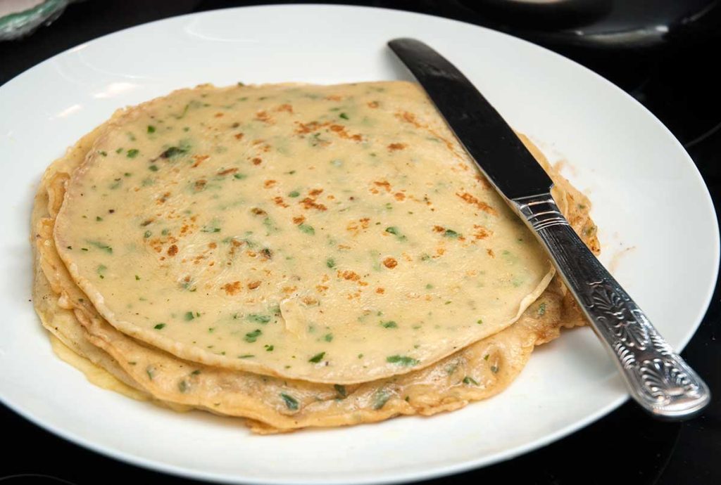 Pancakes with chives stack on a plate.