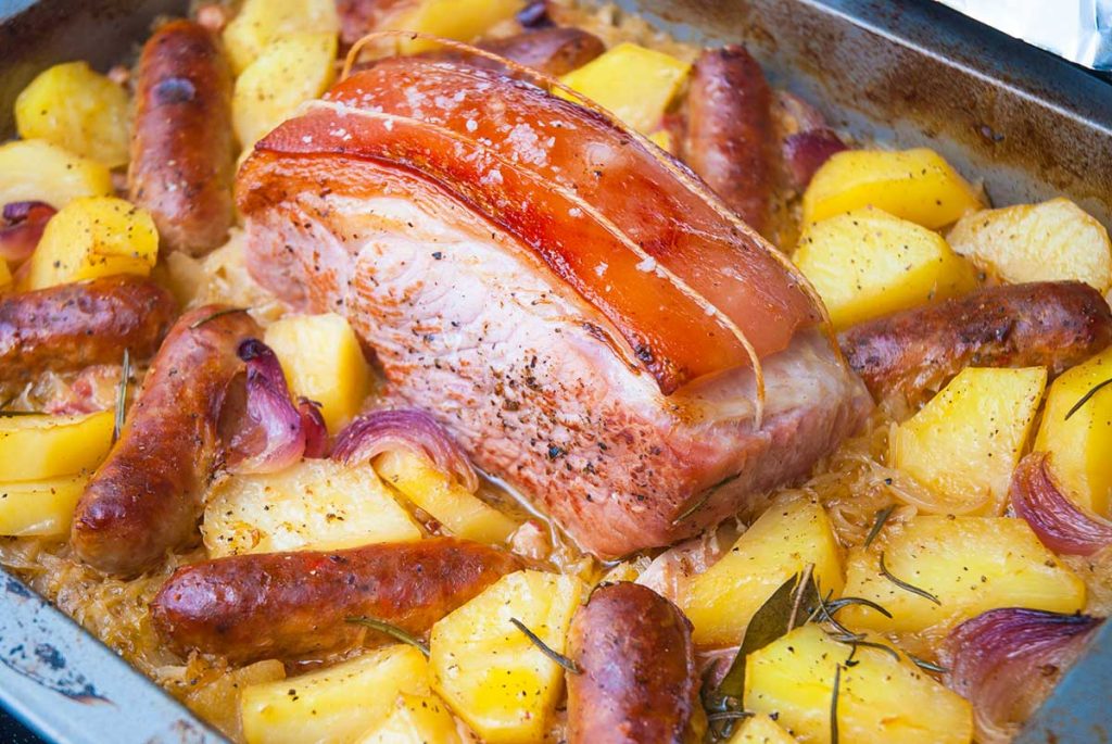 Perfectly roasted boneless pork joint with sausages and potato and sauerkraut.