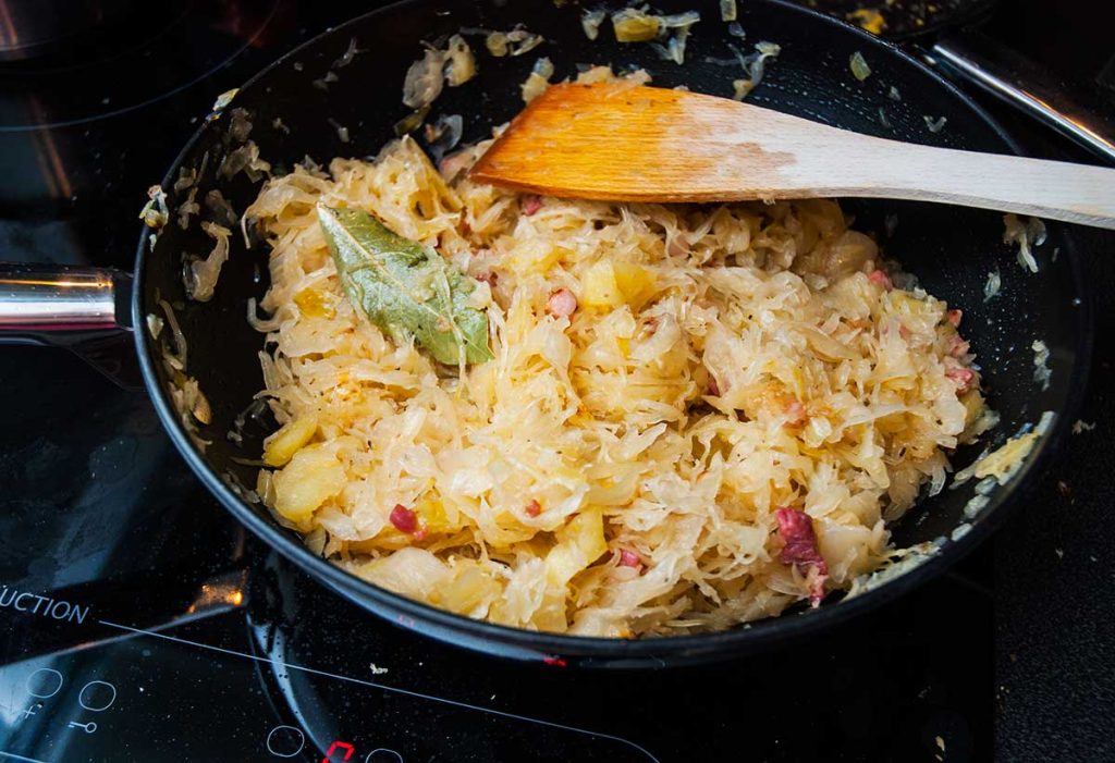 Sauerkraut with bacon, onions and apples cooking a large pan. 