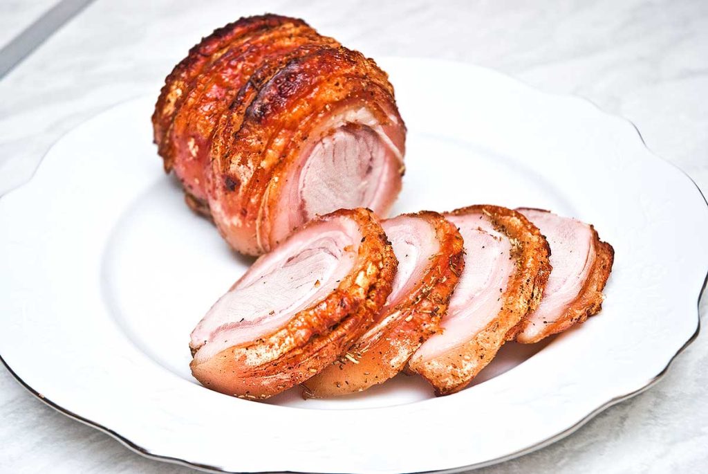 Perfectly roasted pork loin , sliced on a white plate. 