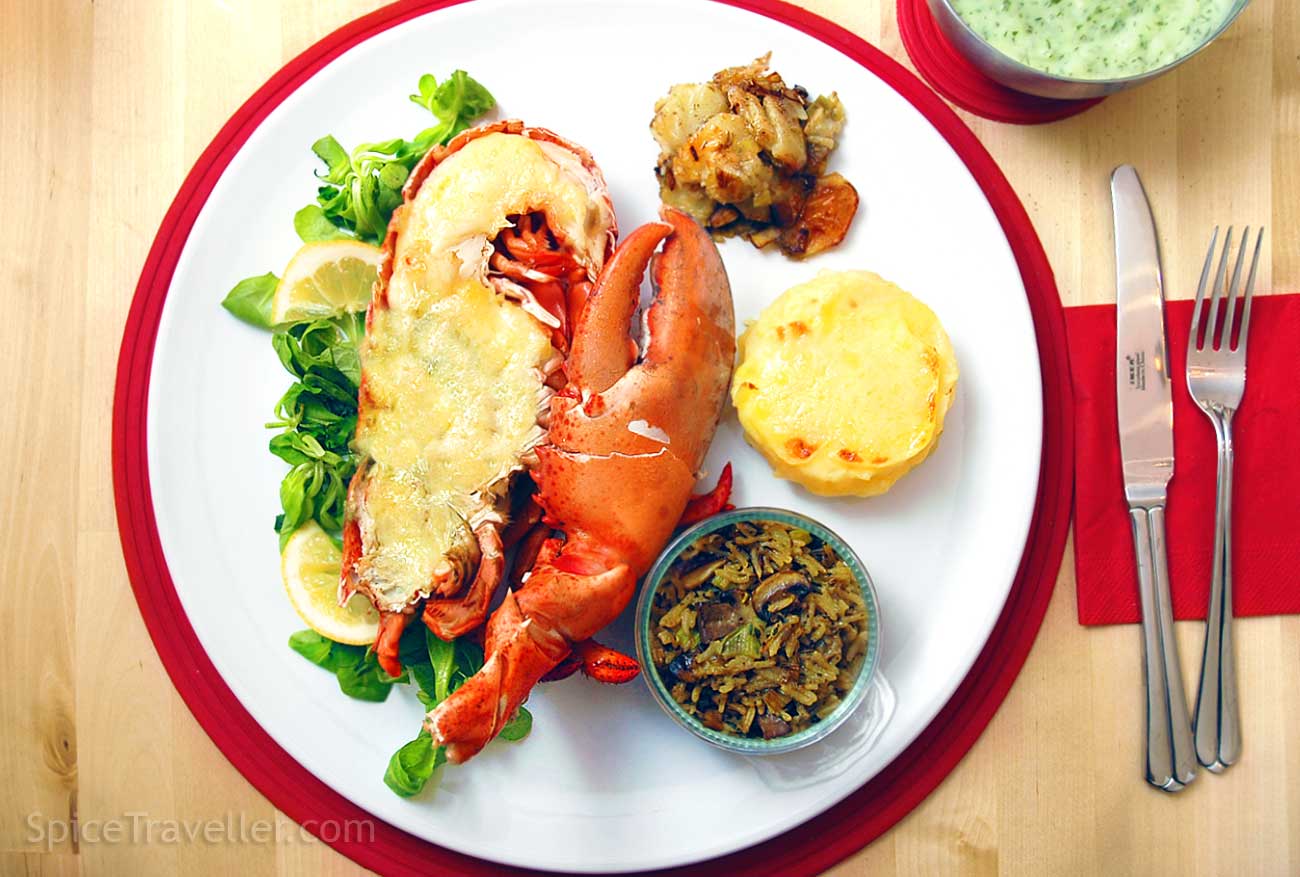 Beautifully presented Classic Lobster Thermidor in halved shell, served with green salad and three different side dishes.