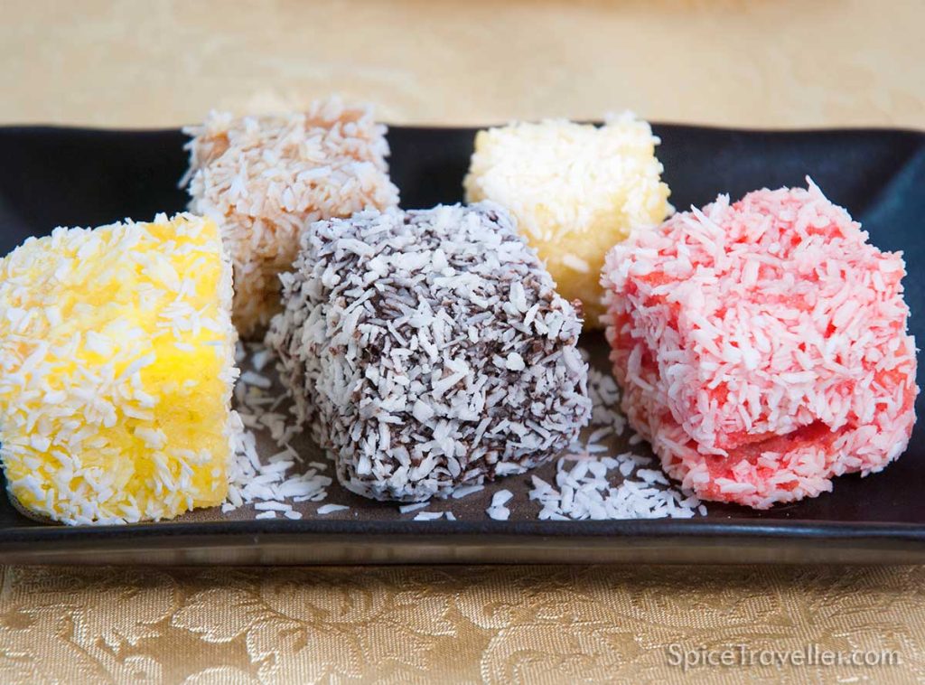 Five Lamingtons with different colours: classic chocolate, rum-punch pink, lemon yellow, white chocolate and carame colour Baileys and walnut. 