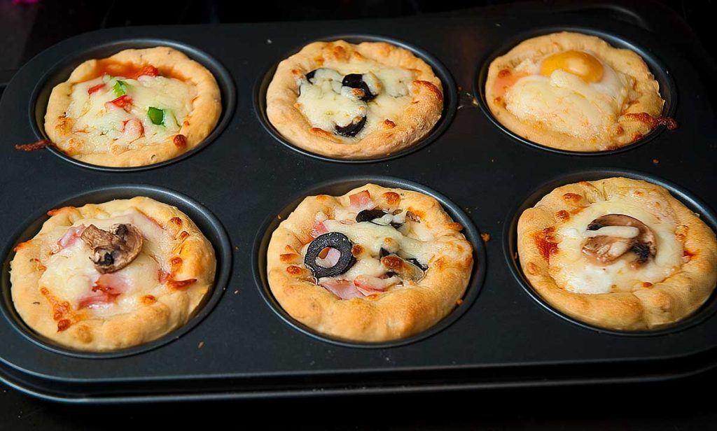 Freshly baked mini pizza cupcakes in a muffin tray.