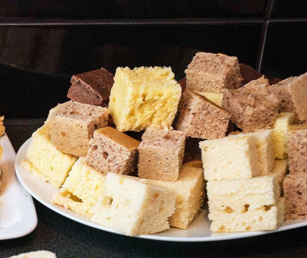 Lamington sponge cake squares in various flavours piledona plate, ready for drizzling and glazing. 