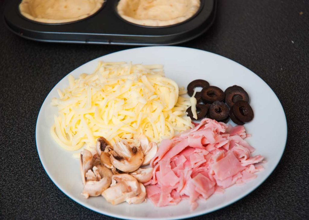 Prepared ingredients; Sliced black olives, grated cheese, sliced mushrooms and ham cut into strips.