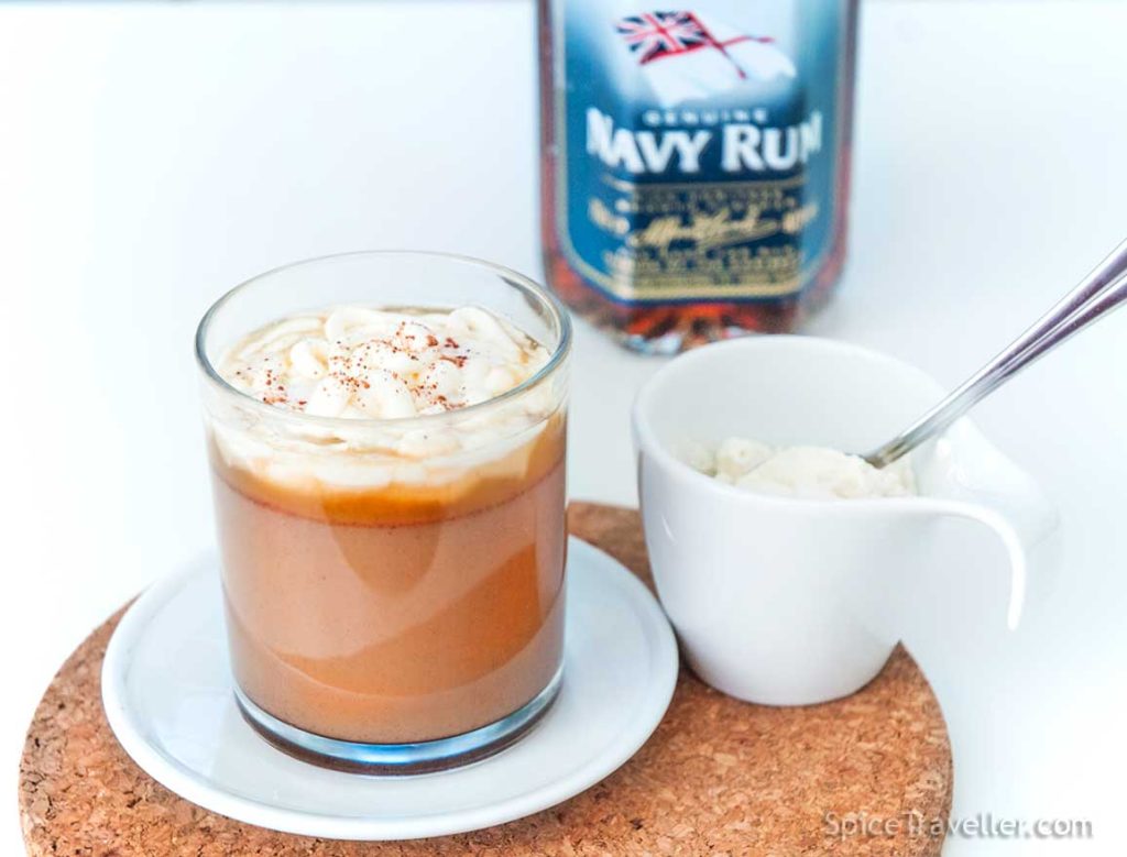 Hot buttered rum topped with double cream served with a small pot of double cream next to the Navy rum bottle.