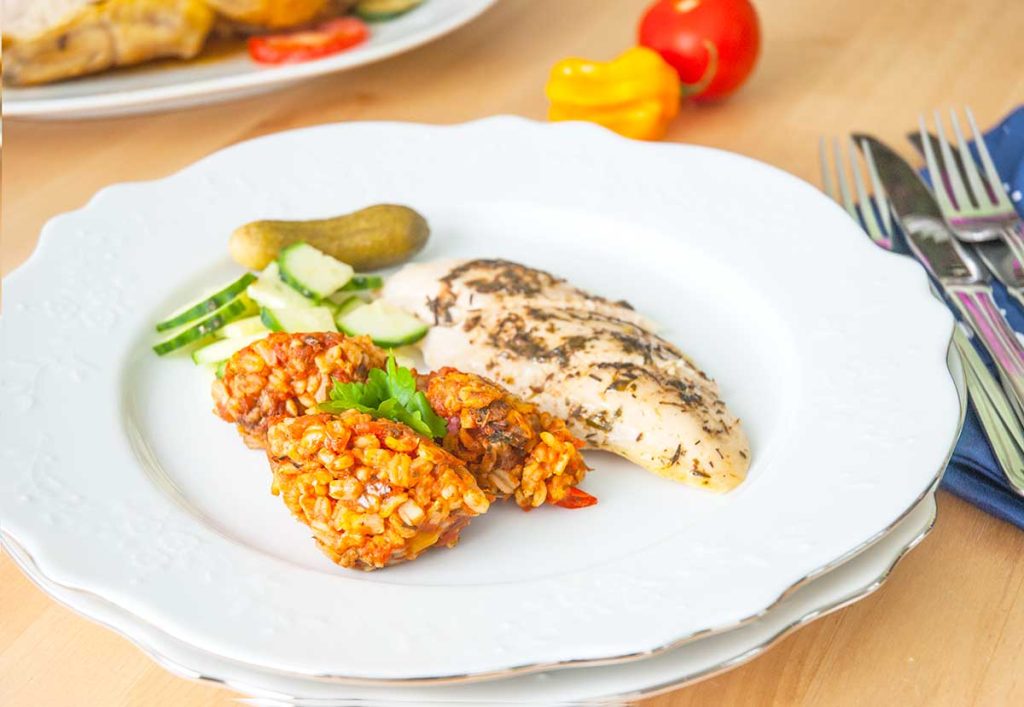 Serving suggestion - Roasted chicken breast, skin removed with three scoops of rice stuffing, one gherking and a few slices of cucumber.