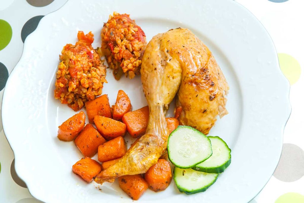 Serving suggestion - Rosted chicken leg with two scoops of rice stuffing , carrots and cucumber slices. 