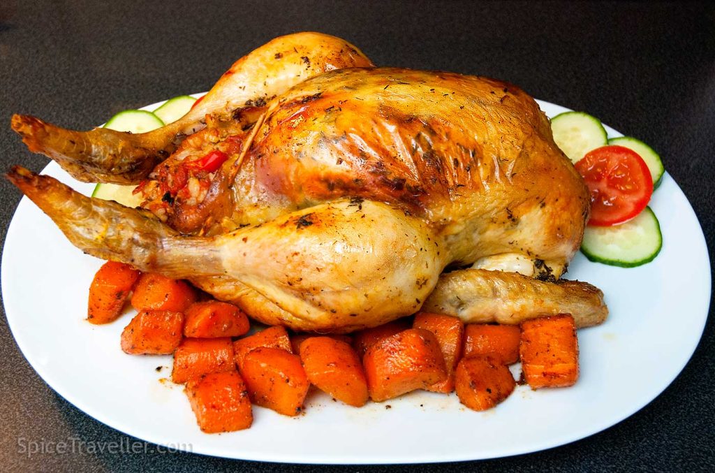 Whole chicken roast served with roasted carrot on a large white oval plate