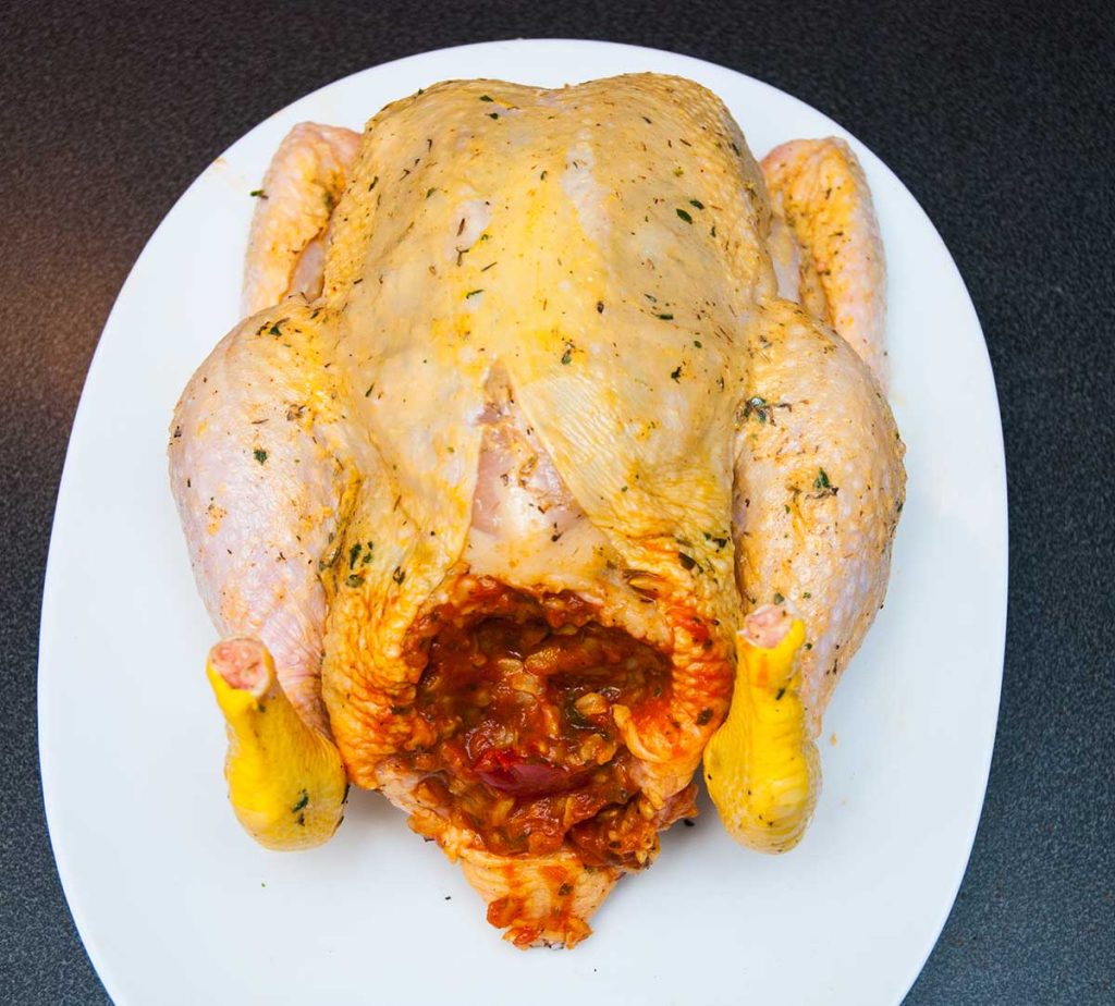 Whole chicken stuffed with rice, pepper and tomato mixture, ready to roast.