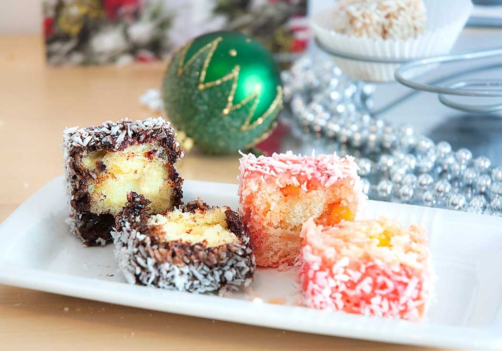 Classic Lamington and rum punch cut in half showing fluffy insides. 