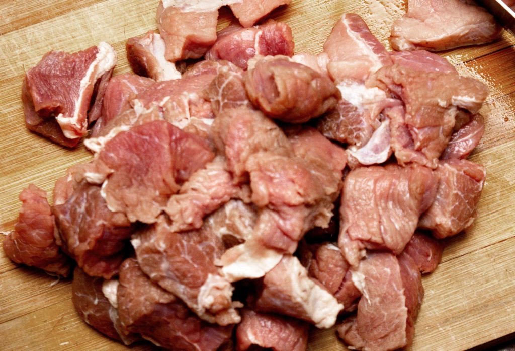 Pork shoulder pieces on a wooden cutting board.