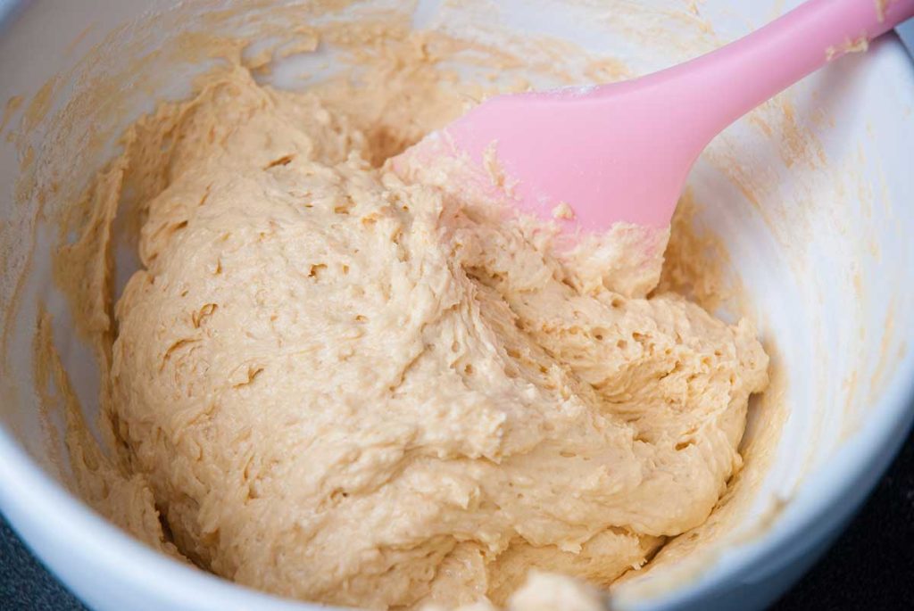 Mixing coconut dough in a white bowl.