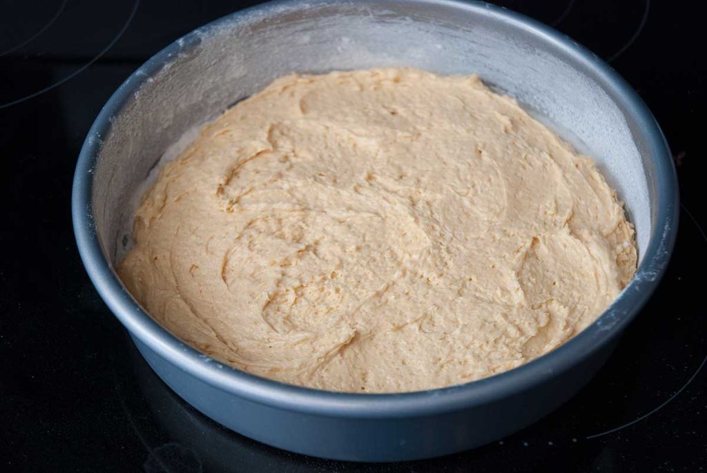 Coconut dough spread in a round shallow baking dish. 