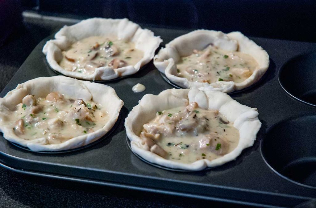 Puff pastry filled with chicken and mushroom sauce while in the cupcake tray moulds.