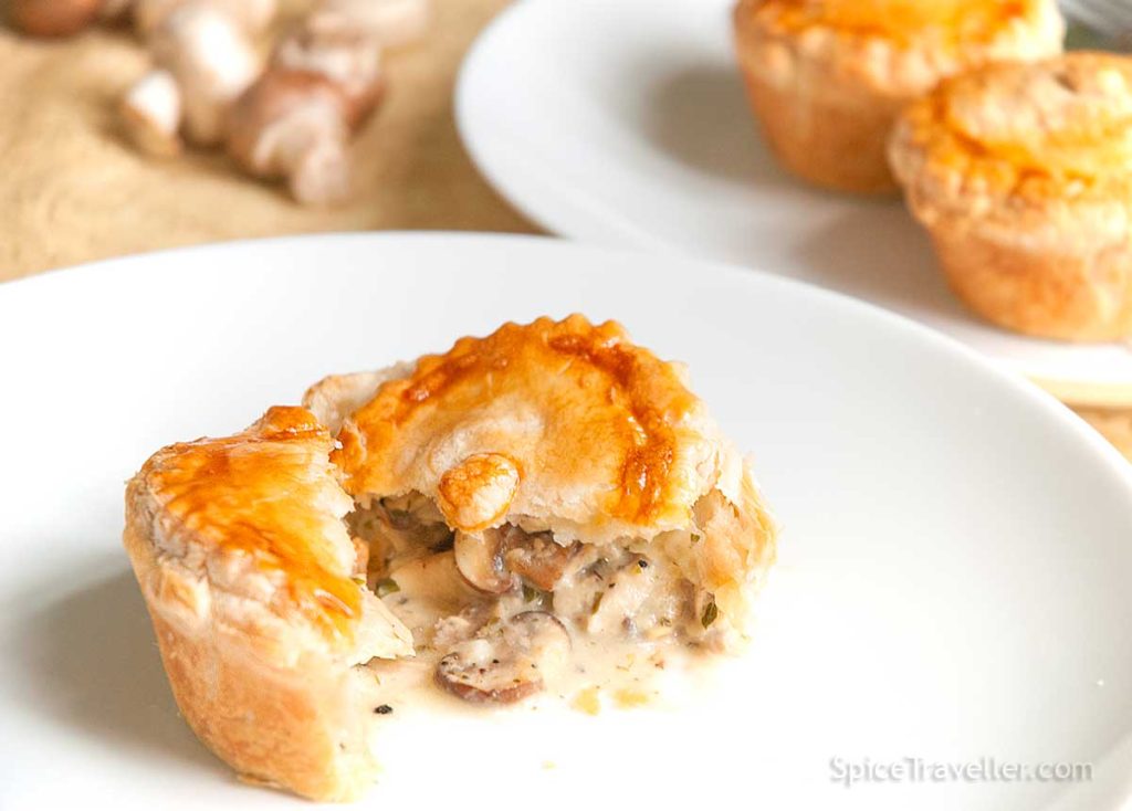 Close-up of the mini chicken and mushroom pie cut in half with delicious creamy filling oozing out.