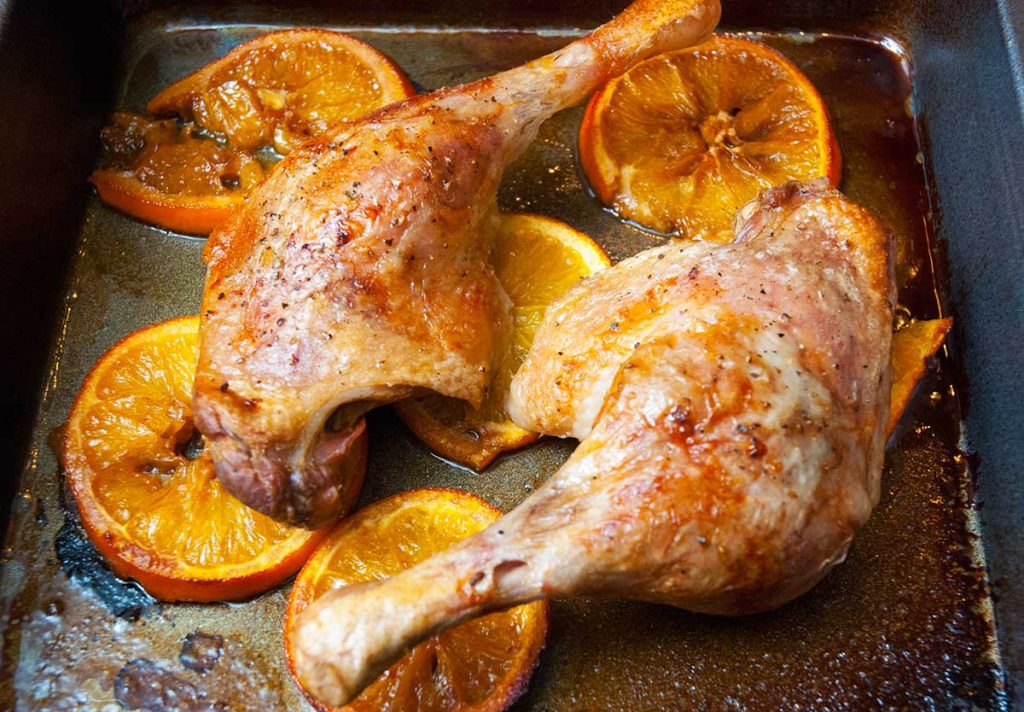 Roasted chicken legs with orange slices. 