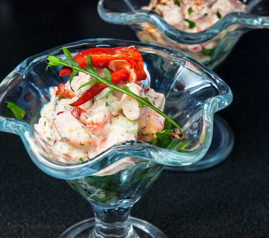 Close up of delicious seafood cocktail with yoghurt and lemon dressing, garnished with langoustine claw meat and wild rocket leaf.