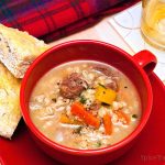 Red soup cup full of hearty Scotch Broth served with Bannock bread.