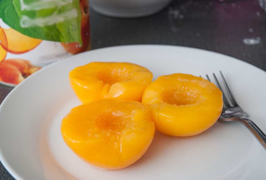 Preserved peach halves on a plate.