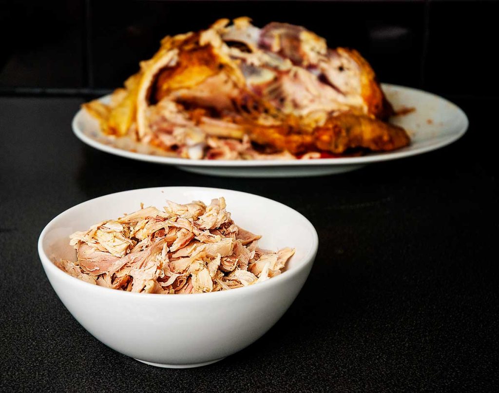 Shredded roasted chicken in a white bowl