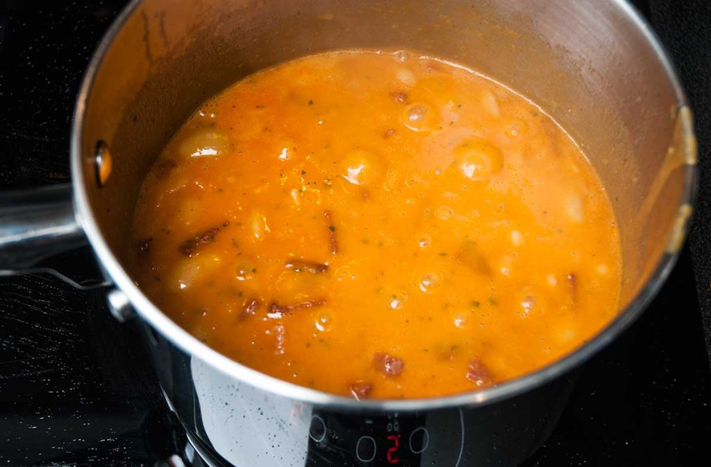 Butter beans with other ingredients simmering in a pot.