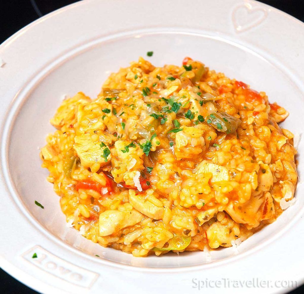 An elegant deep plate with Brazilian Galinhada - chicken and rice, garnished with parsley. 