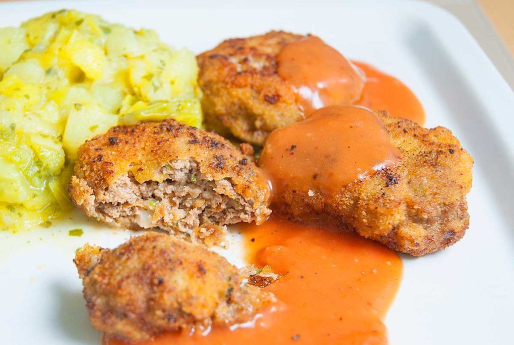 Close up of rissoles ( beef patties ) cut in half served with gravy and a leek mash. 