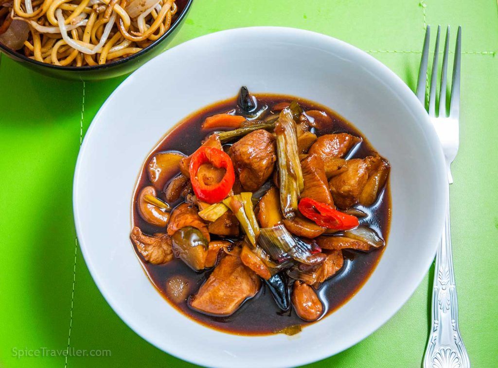 Bowl of dark Thai Jungle chicken curry garnished with fresh red chili