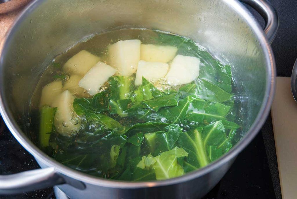 Boiling potato chunks with chopped chard.