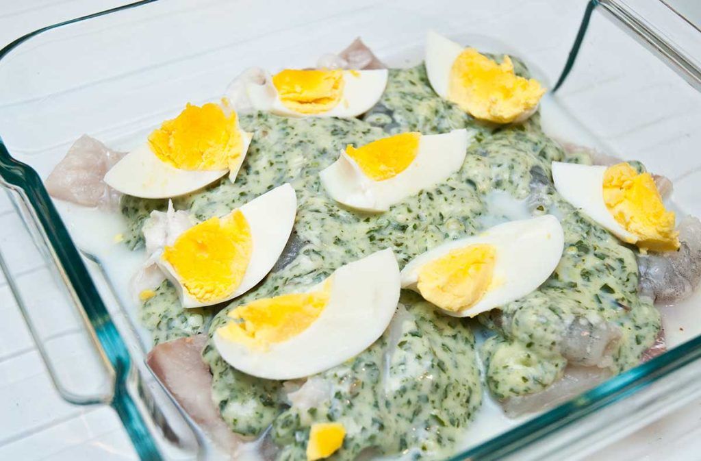 British fish pie layering, showing ingredients, fish , sauce and hard boil egg pieces.
