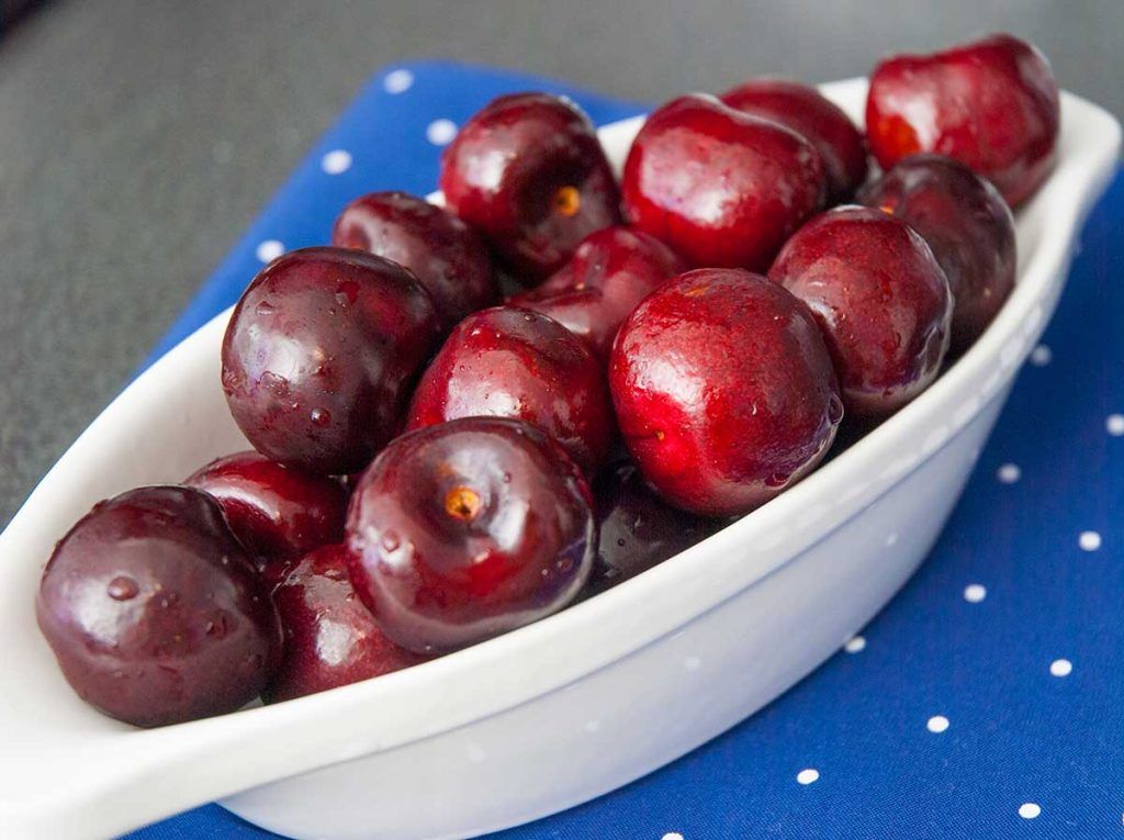 Bowl of fresh large dark red cherries.