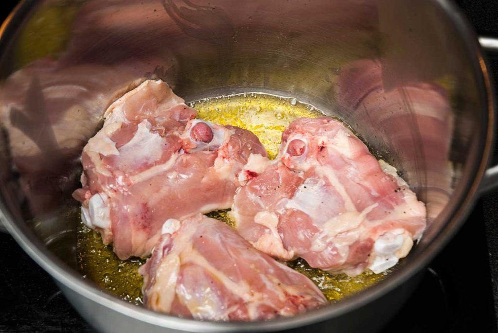 Frying 3 large chicken thighs in a pot.