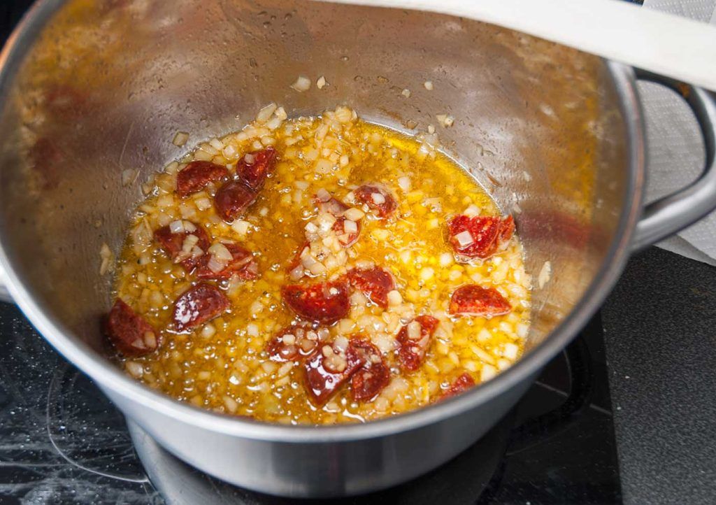 Frying chopped Chorizo sausages with onions.