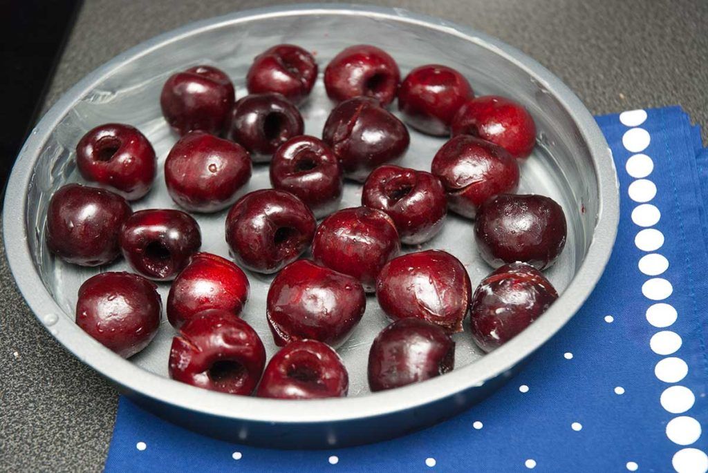 Pitted cherries layered in a baking dish ready to make French custard cake with cherries , Clafoutis.