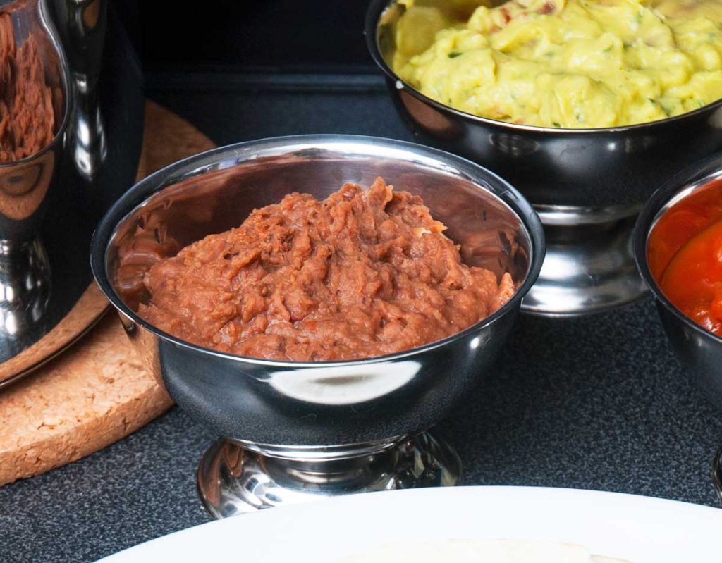 Close up of refried beans in a metal serving bowl.