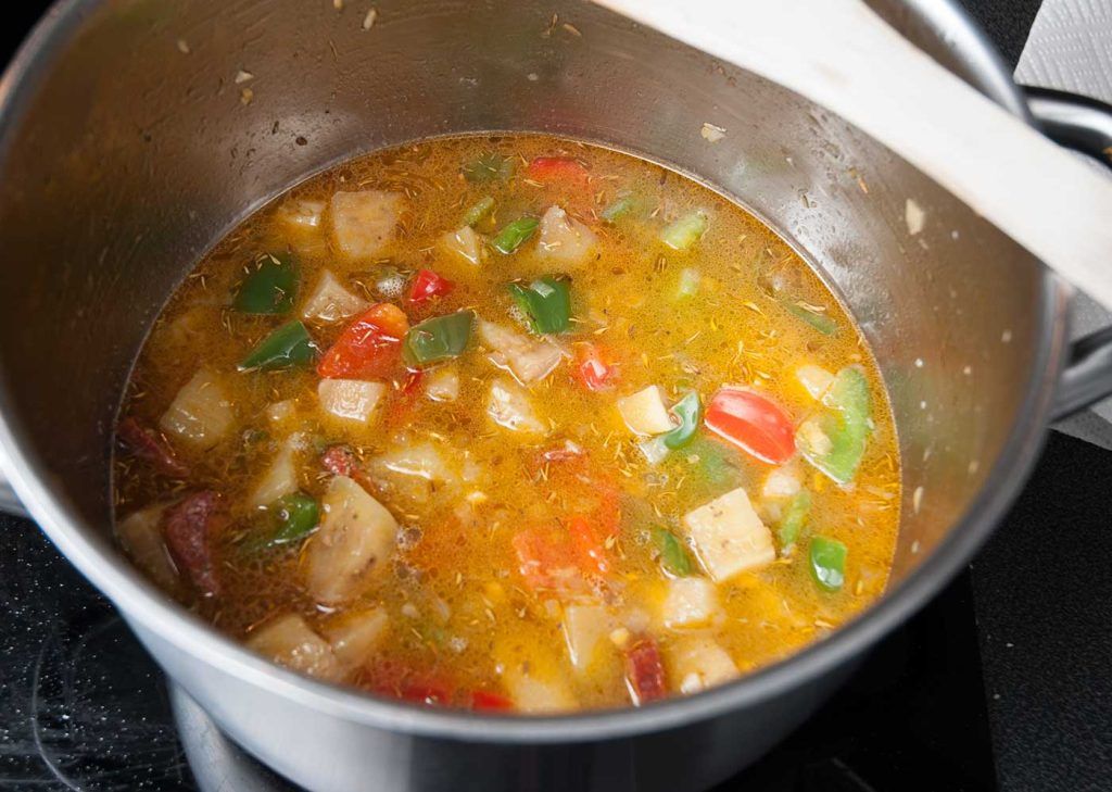 Cooking bulgur and vegetables in a broth.