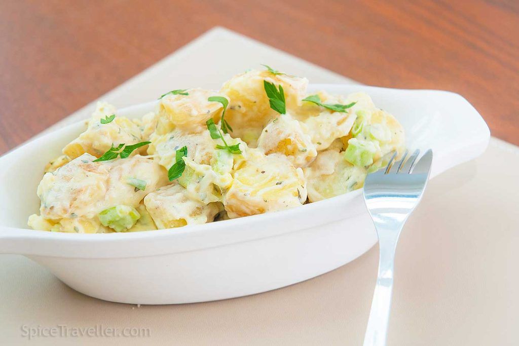 Close up of British potato salad deli style, served in a small oval dish.