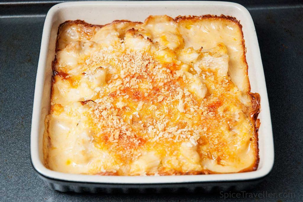 Freshly baked cauliflower cheese in a small rectangular baking dish, golden on top with melted cheese and crisp breadcrumbs.