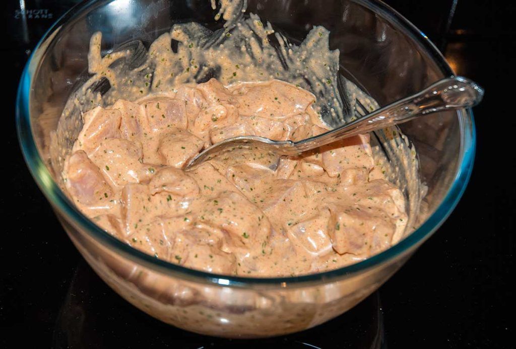 Marinated chicken pieces in a glass bowl.