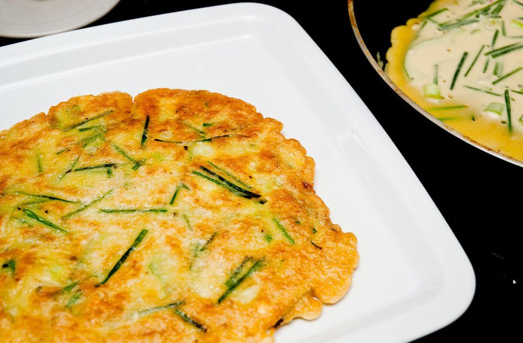 Korean chive pancake on a plate and another still frying.