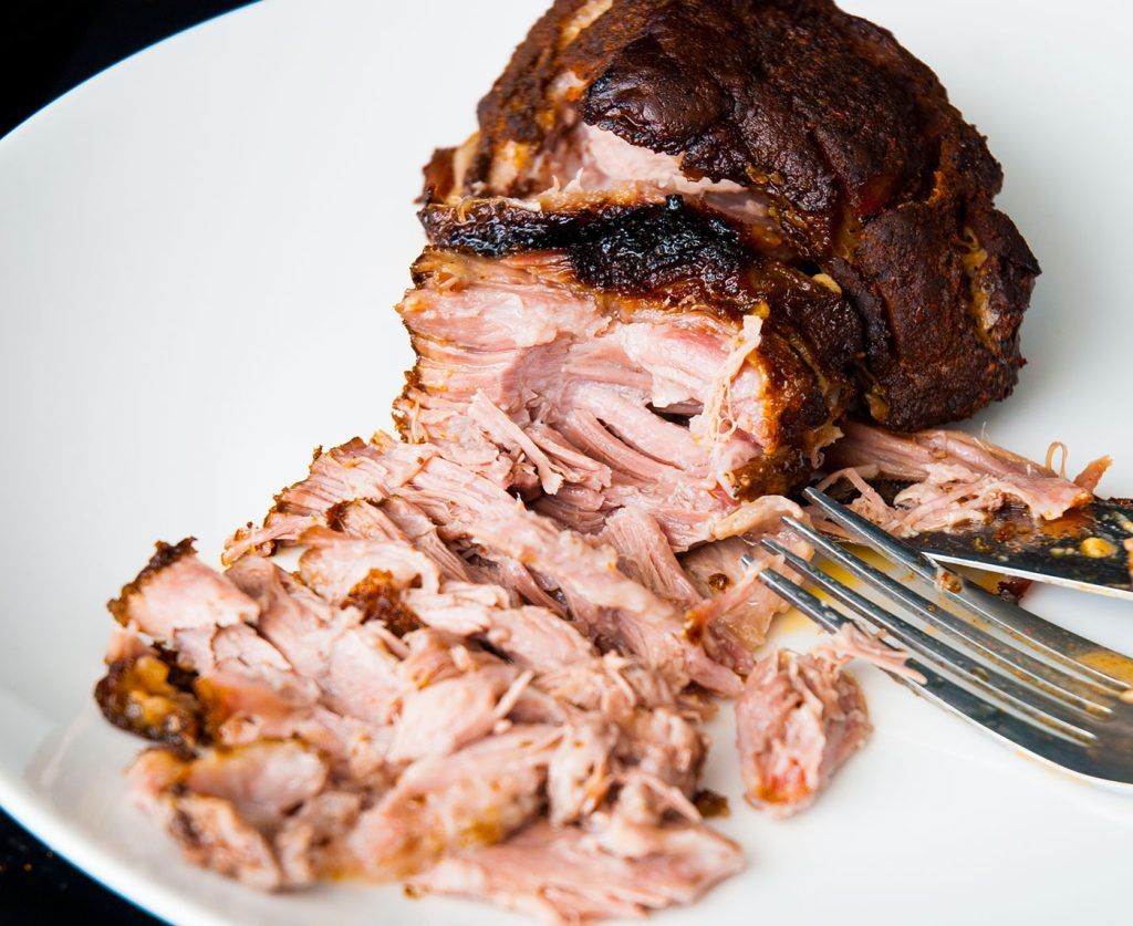 Partially shredded pork roast on a plate, ready to be mixed with minced pork and used to fill Tourtiere meat pies.